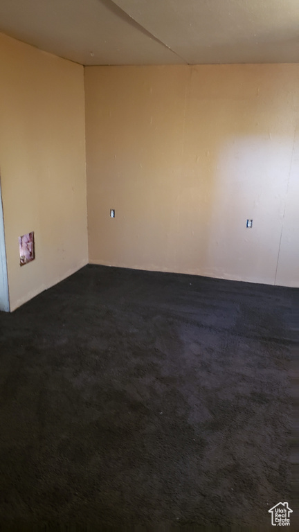 Spare room featuring dark colored carpet