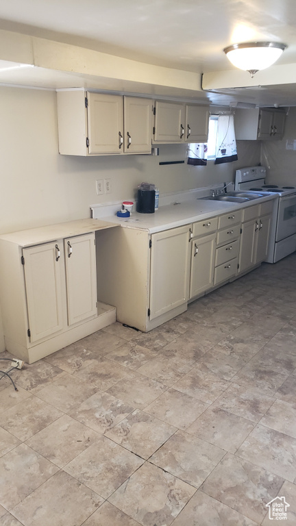 Kitchen featuring white range with electric cooktop, light countertops, and a sink