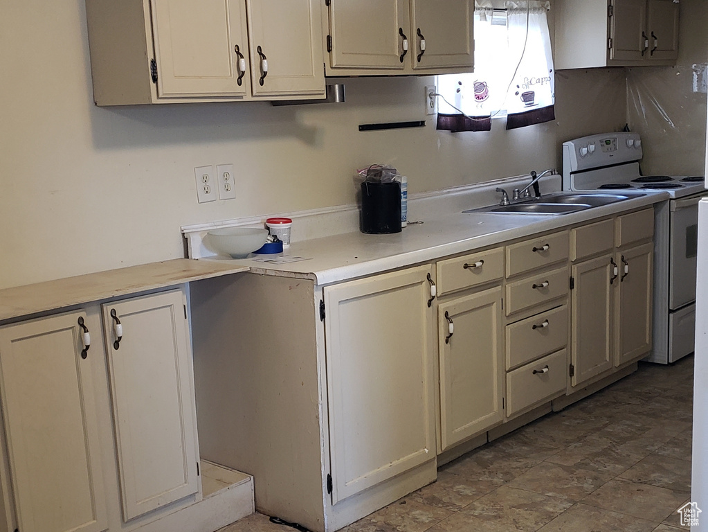 Kitchen featuring light countertops, white electric stove, and a sink