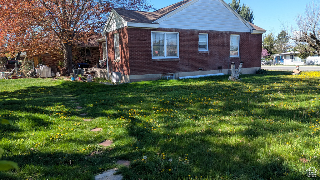 View of property exterior featuring a lawn and brick siding