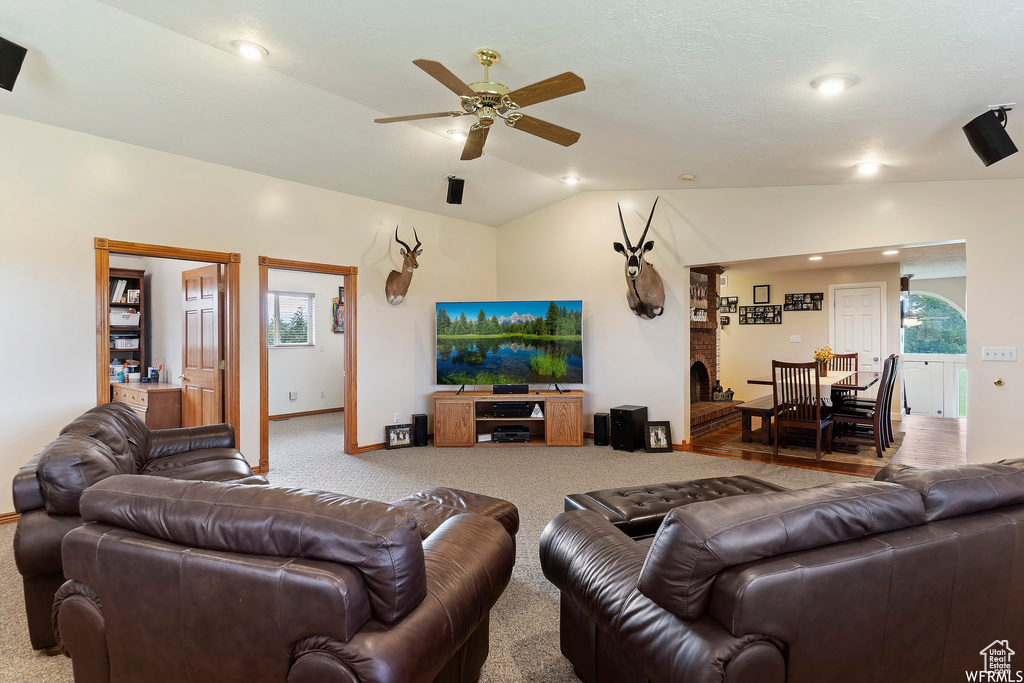 Carpeted living room with ceiling fan, vaulted ceiling, and a wealth of natural light