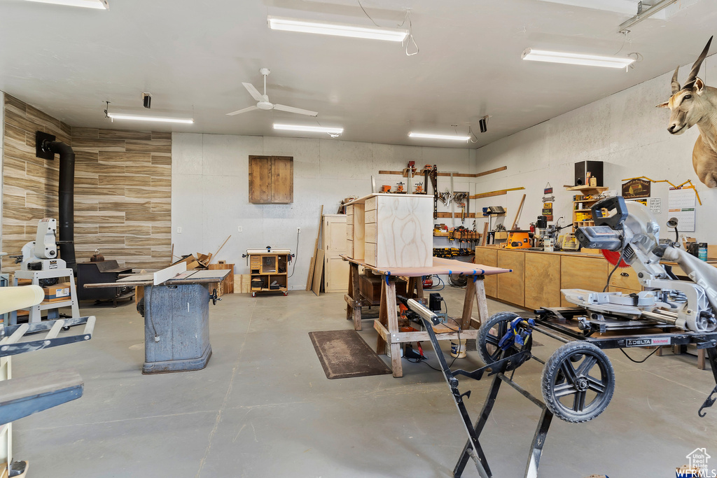 Garage featuring ceiling fan, a workshop area, and a wood stove