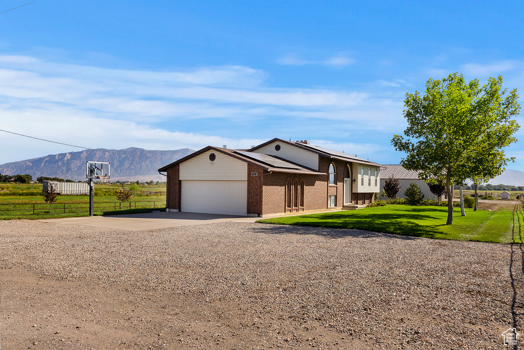 View of front facade with a mountain view, a front yard, and a garage