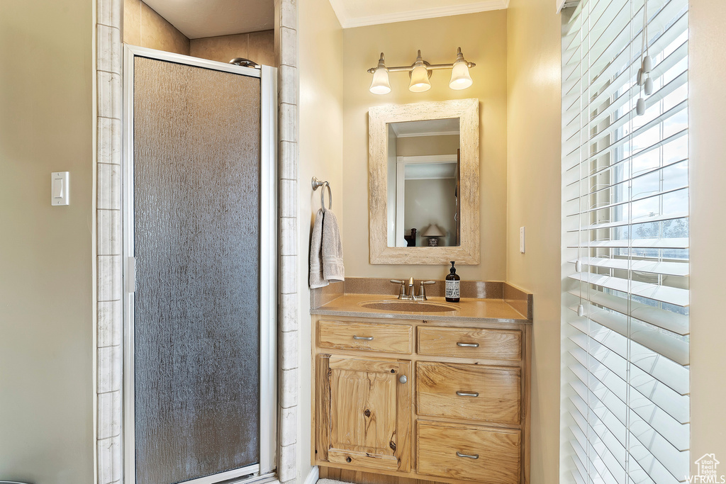 Bathroom with vanity, ornamental molding, and an enclosed shower