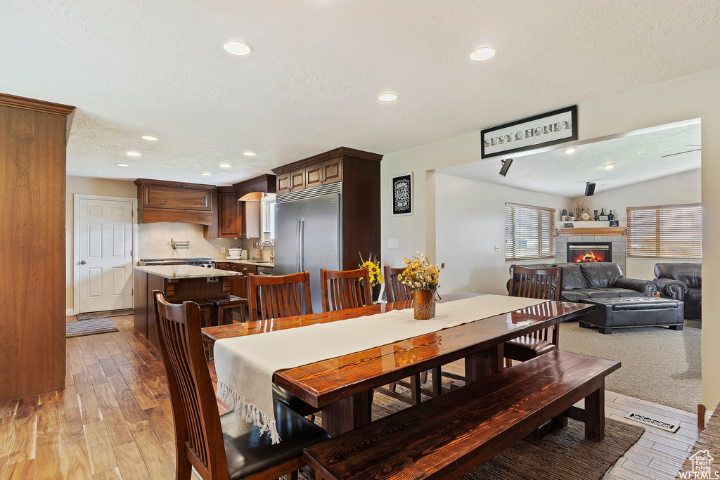 Dining room with hardwood / wood-style floors, lofted ceiling, a tile fireplace, and a textured ceiling
