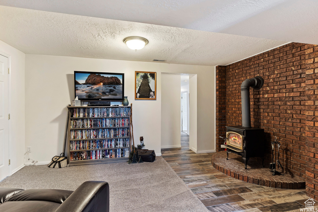 Living room with hardwood / wood-style flooring, a wood stove, and a textured ceiling