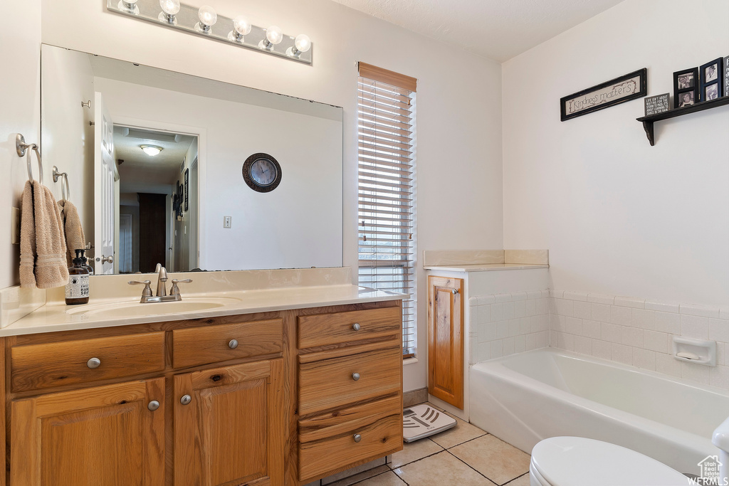 Bathroom featuring plenty of natural light, a washtub, tile patterned floors, and vanity