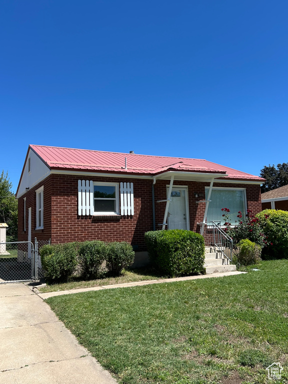 Single story home with brick siding, a front lawn, and metal roof