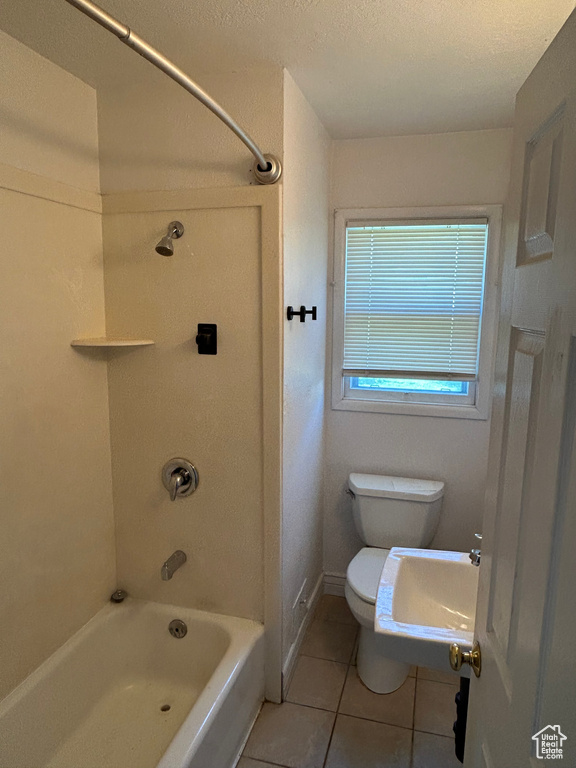 Full bath featuring tile patterned flooring, shower / washtub combination, toilet, and a textured ceiling
