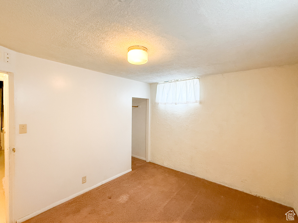 Unfurnished room featuring a textured ceiling and light carpet