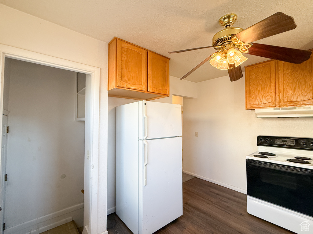 Kitchen featuring a textured ceiling, electric range, ceiling fan, white refrigerator, and dark hardwood / wood-style floors