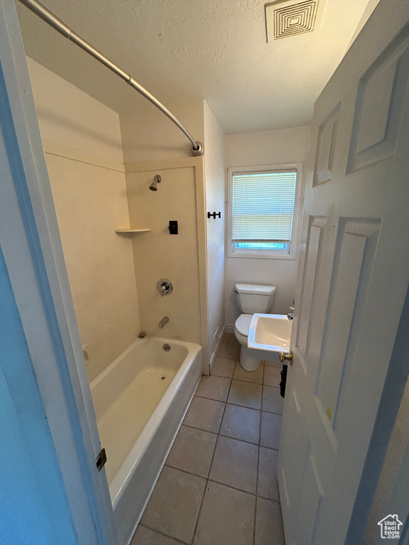 Full bathroom featuring a textured ceiling, toilet, tile patterned floors, shower / bath combination, and a sink