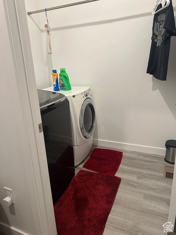 Laundry room with washer and dryer and wood-type flooring