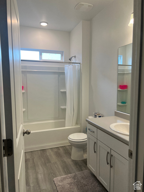 Full bathroom with vanity, hardwood / wood-style flooring, shower / bathtub combination with curtain, and toilet
