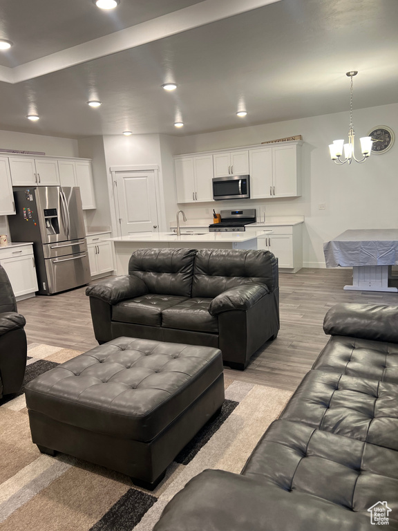 Living room featuring sink, a tray ceiling, light hardwood / wood-style flooring, and a chandelier