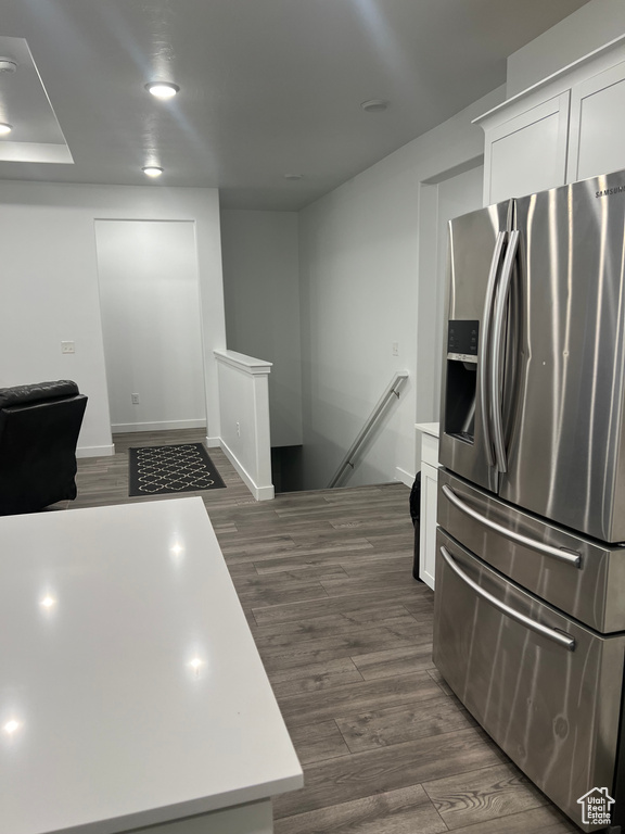 Kitchen with white cabinetry, dark hardwood / wood-style floors, and stainless steel refrigerator with ice dispenser