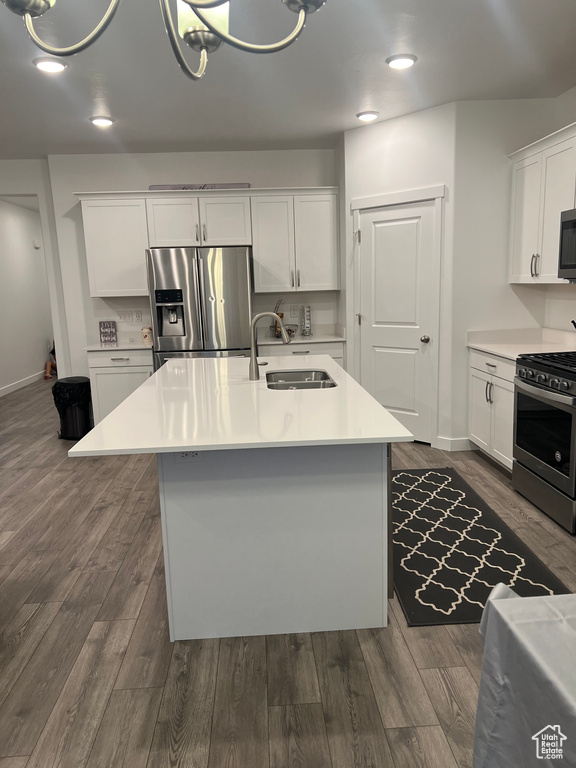 Kitchen featuring white cabinetry, stainless steel appliances, sink, dark hardwood / wood-style floors, and a center island with sink