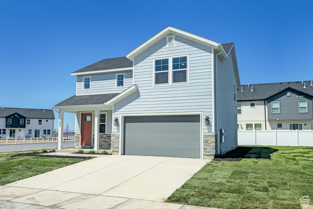 View of front of property featuring an attached garage, driveway, and stone siding