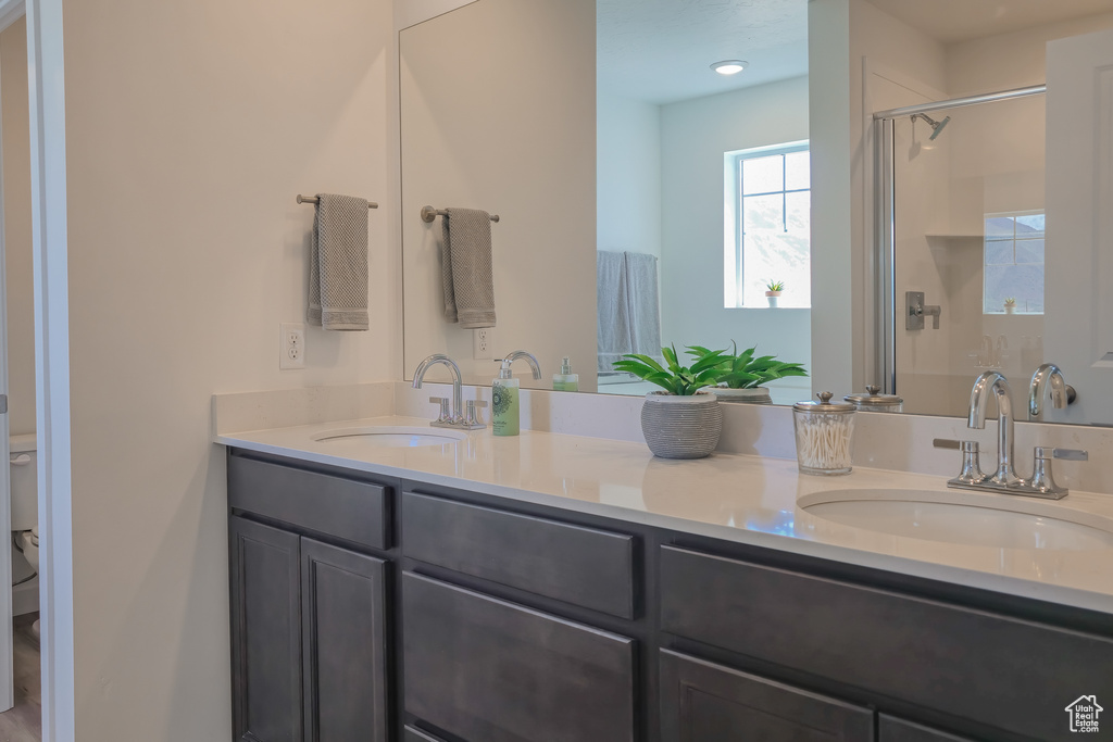 Full bathroom with a shower stall, double vanity, and toilet