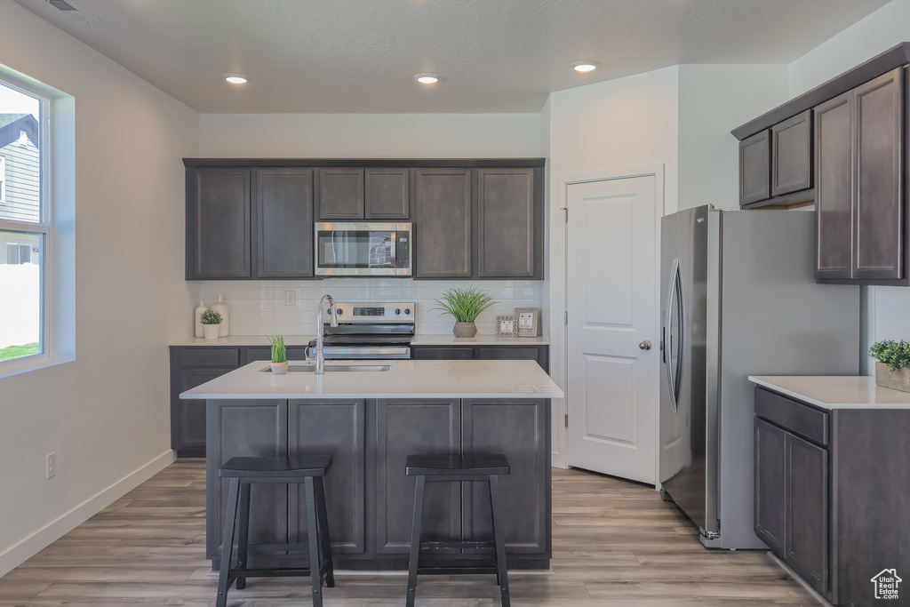 Kitchen featuring stainless steel appliances, light countertops, dark brown cabinets, and recessed lighting
