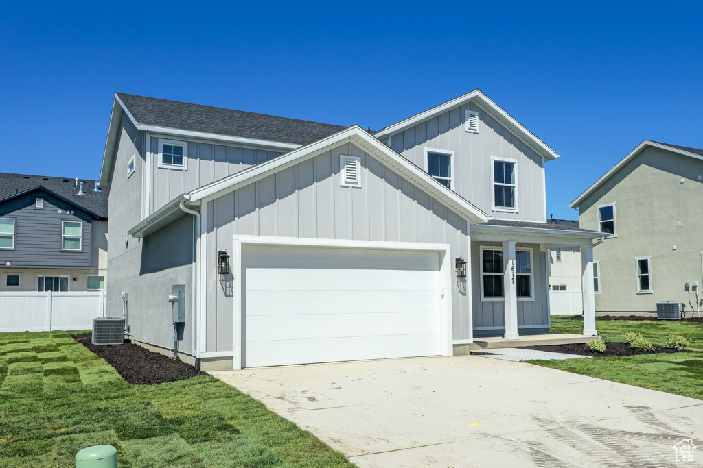 Traditional-style house with board and batten siding, a garage, concrete driveway, and central air condition unit