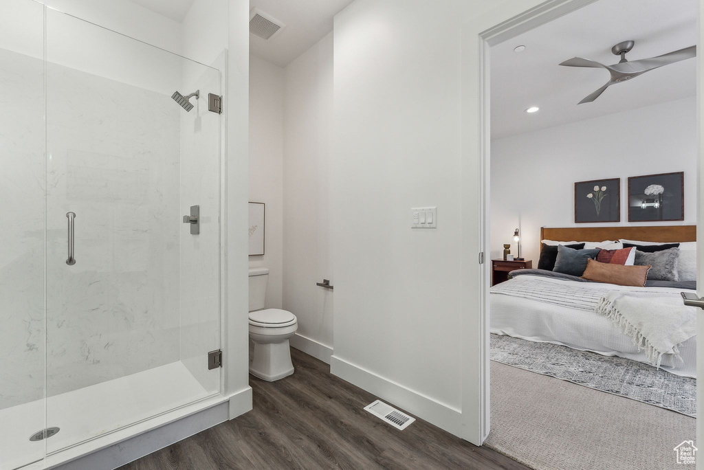 Bathroom with wood-type flooring, a shower with shower door, toilet, and ceiling fan