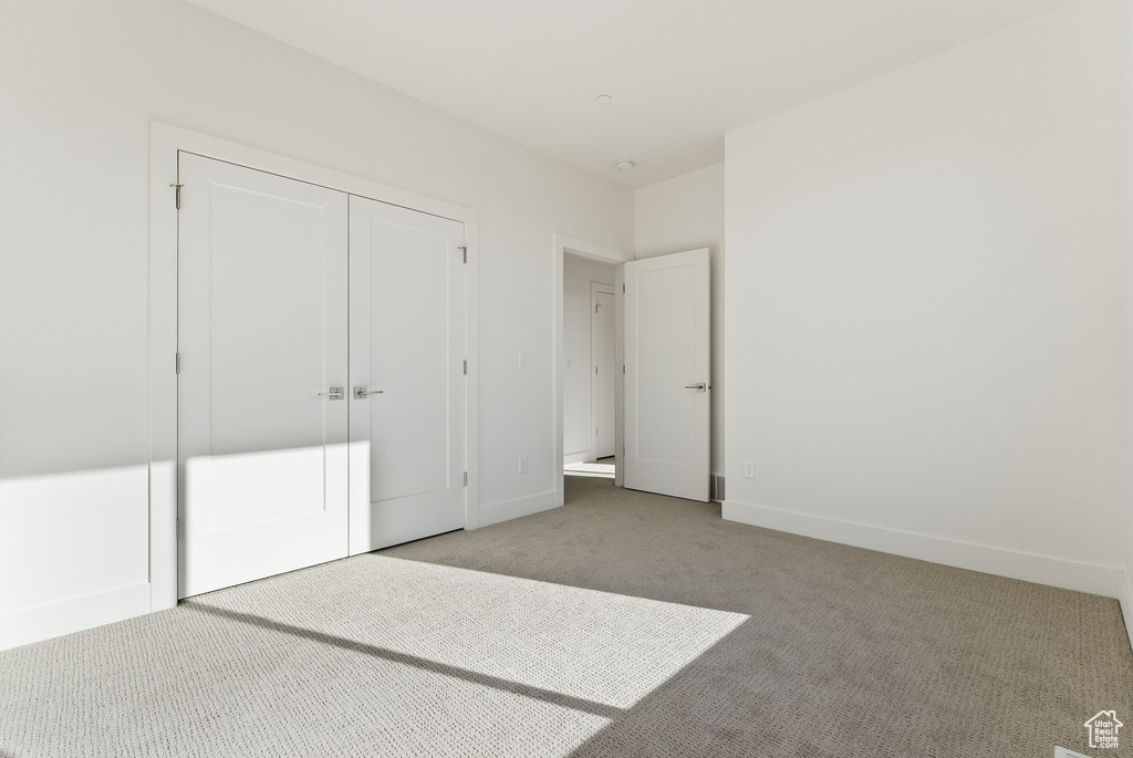 Unfurnished bedroom with light colored carpet and a closet