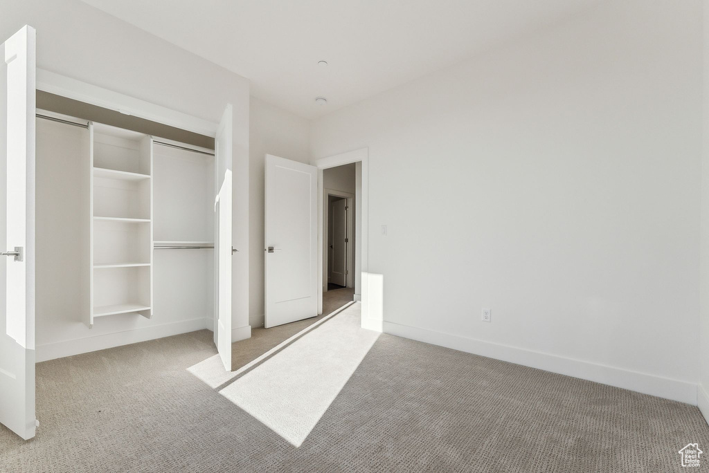 Unfurnished bedroom with light colored carpet and a closet