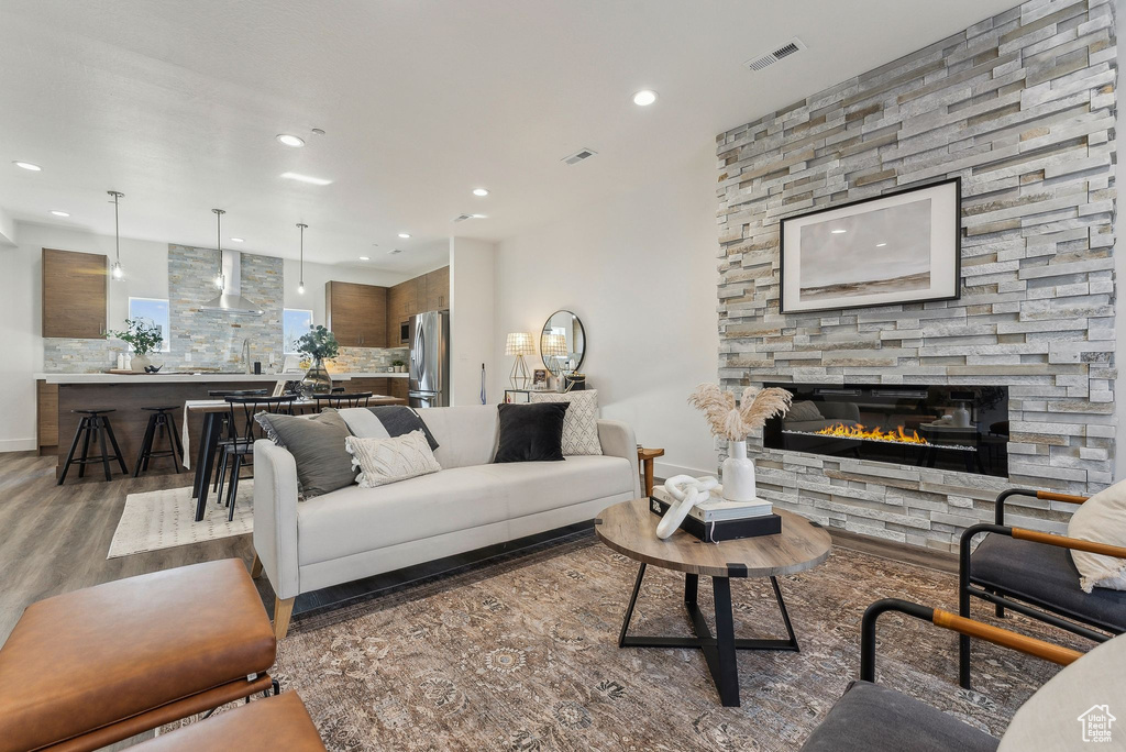 Living room with a stone fireplace and dark wood-type flooring