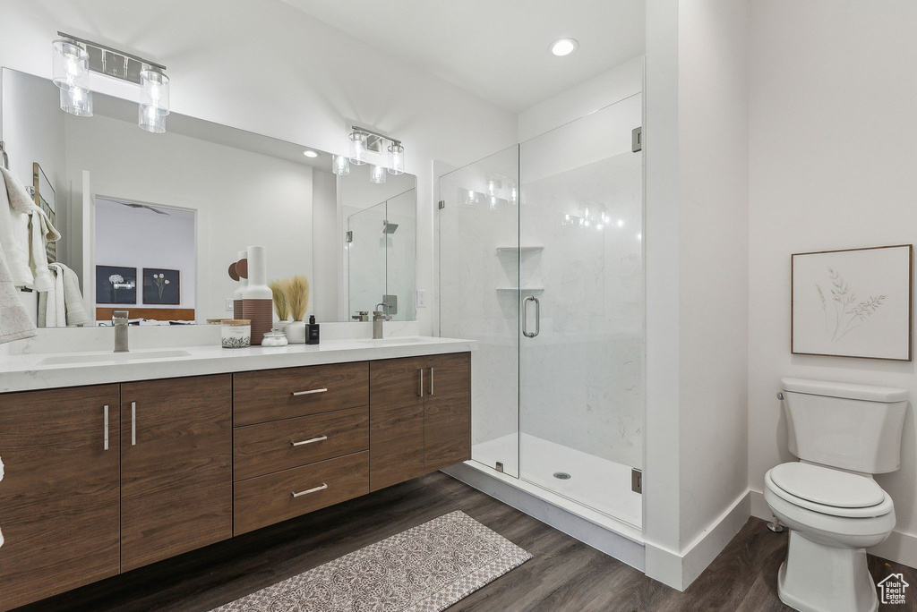 Bathroom with an enclosed shower, vanity, hardwood / wood-style flooring, and toilet