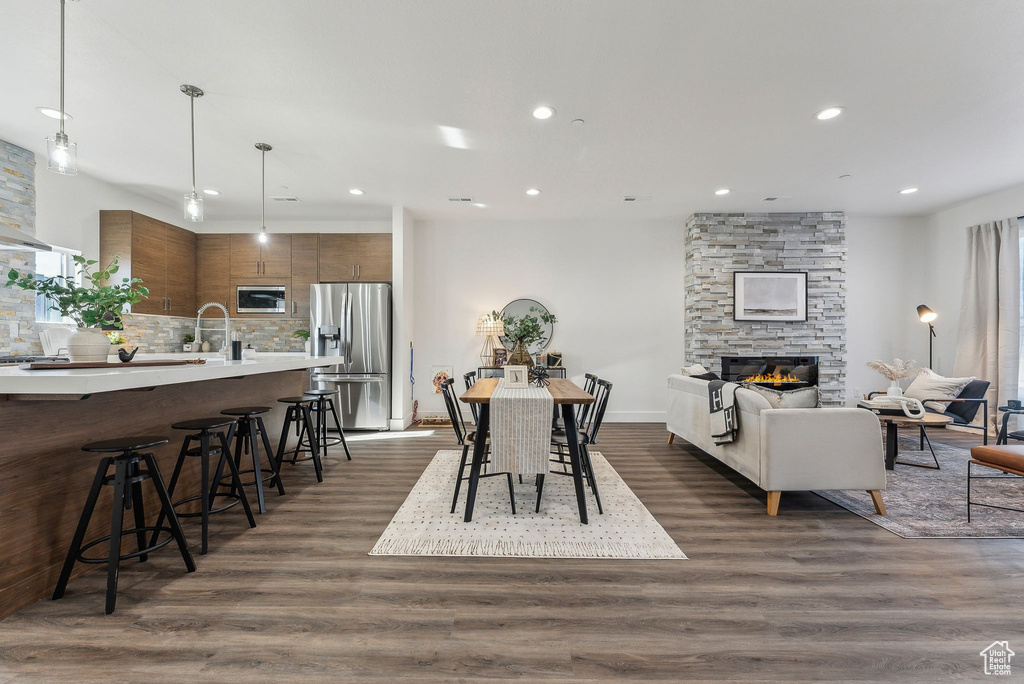 Dining area with sink, a stone fireplace, and dark wood-type flooring