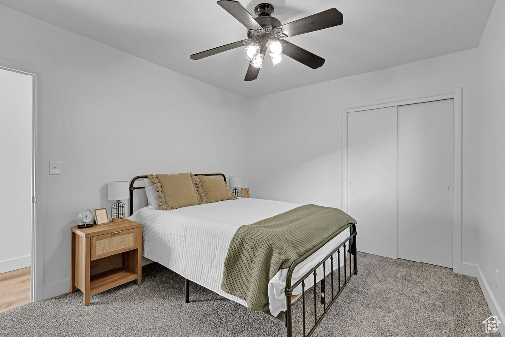 Carpeted bedroom with ceiling fan and a closet