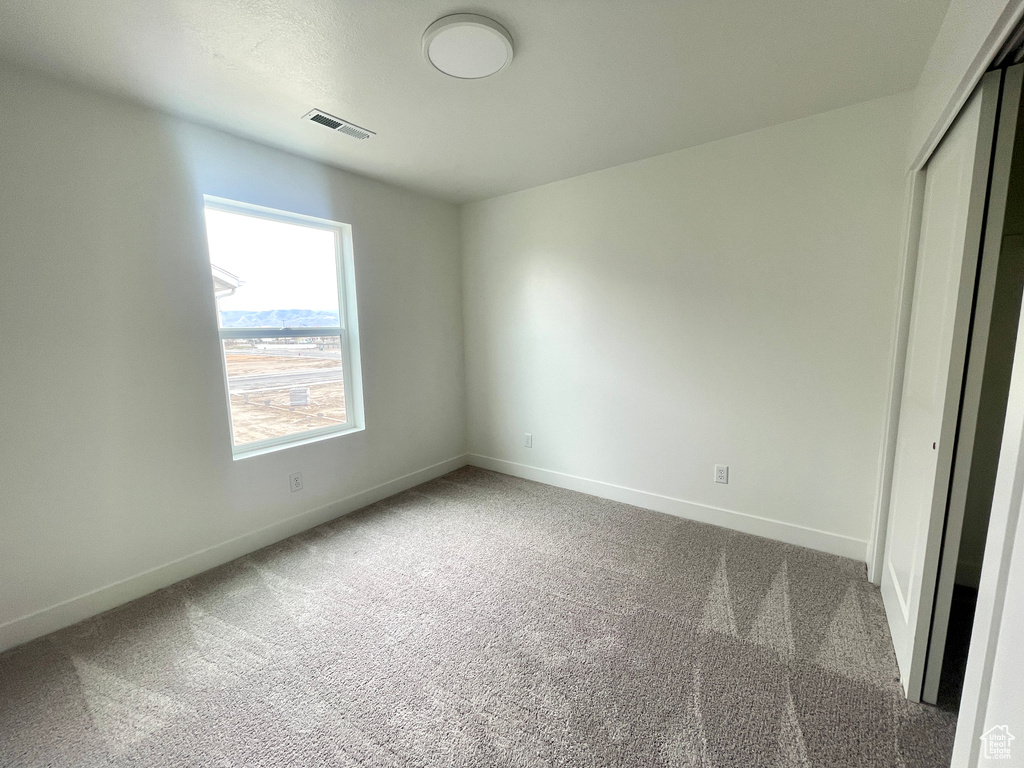 Unfurnished bedroom featuring baseboards, visible vents, a closet, and carpet
