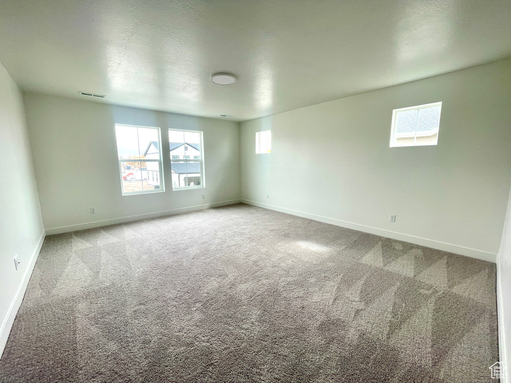 Carpeted empty room with baseboards and visible vents