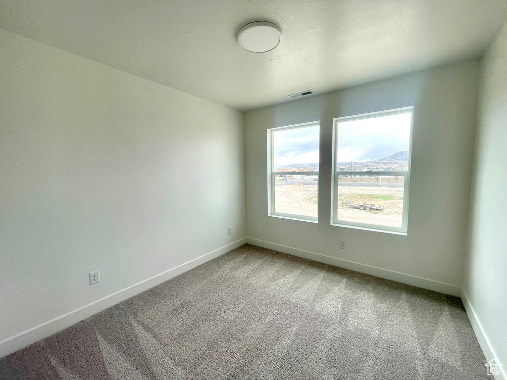 Spare room featuring baseboards, visible vents, and carpet flooring