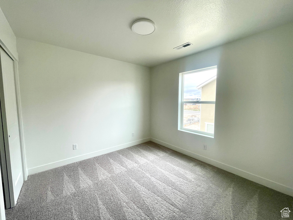 Unfurnished bedroom featuring baseboards, carpet flooring, visible vents, and a closet