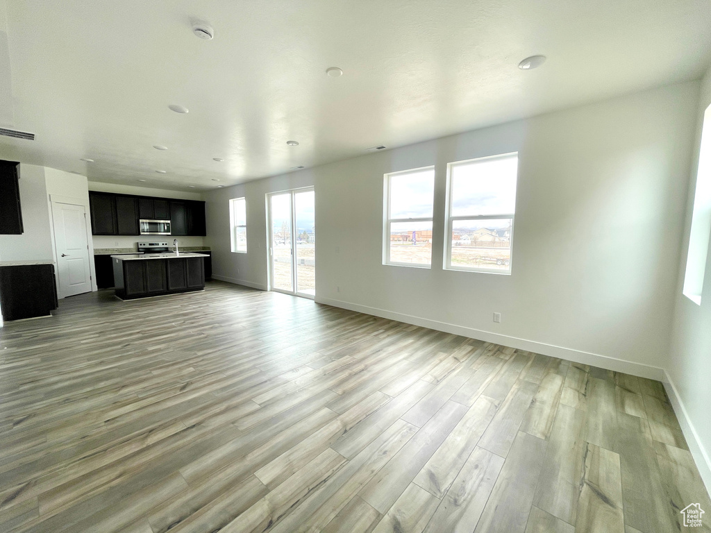 Unfurnished living room featuring baseboards and light wood-style flooring