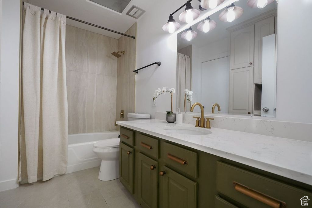 Full bathroom featuring vanity, tile patterned flooring, toilet, and shower / bath combo with shower curtain