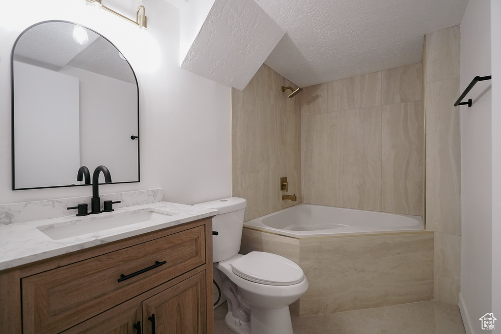 Full bathroom with shower / tub combination, vanity, toilet, and a textured ceiling