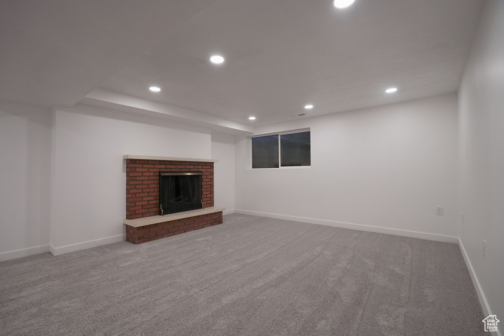 Unfurnished living room featuring a brick fireplace and carpet floors