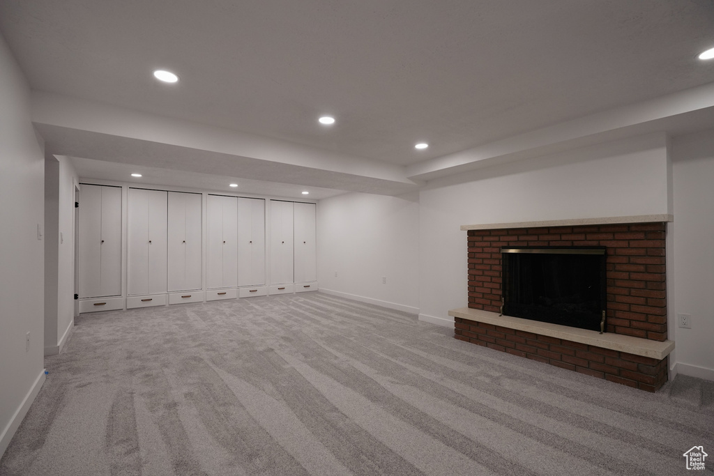 Basement with a fireplace and light colored carpet