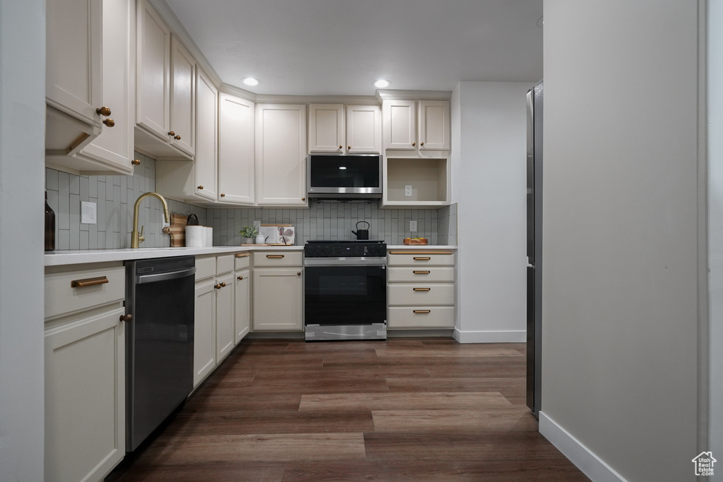 Kitchen featuring tasteful backsplash, white cabinetry, dark hardwood / wood-style flooring, and stainless steel appliances