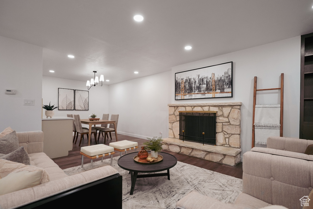 Living room featuring a fireplace, a notable chandelier, and wood-type flooring