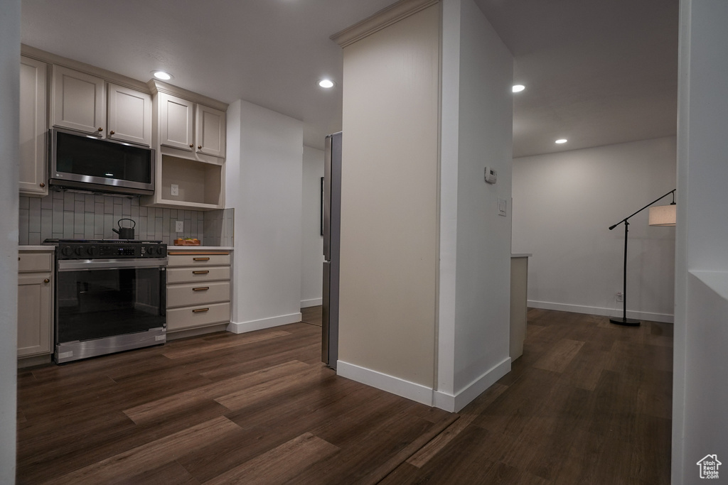 Kitchen with dark wood-type flooring, decorative backsplash, and stove