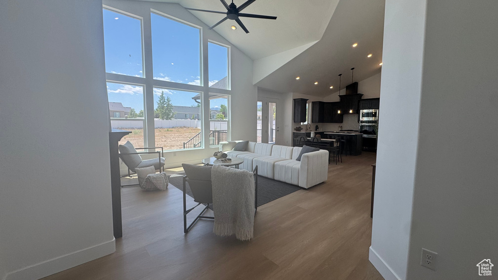 Living area featuring high vaulted ceiling, wood finished floors, ceiling fan, baseboards, and recessed lighting