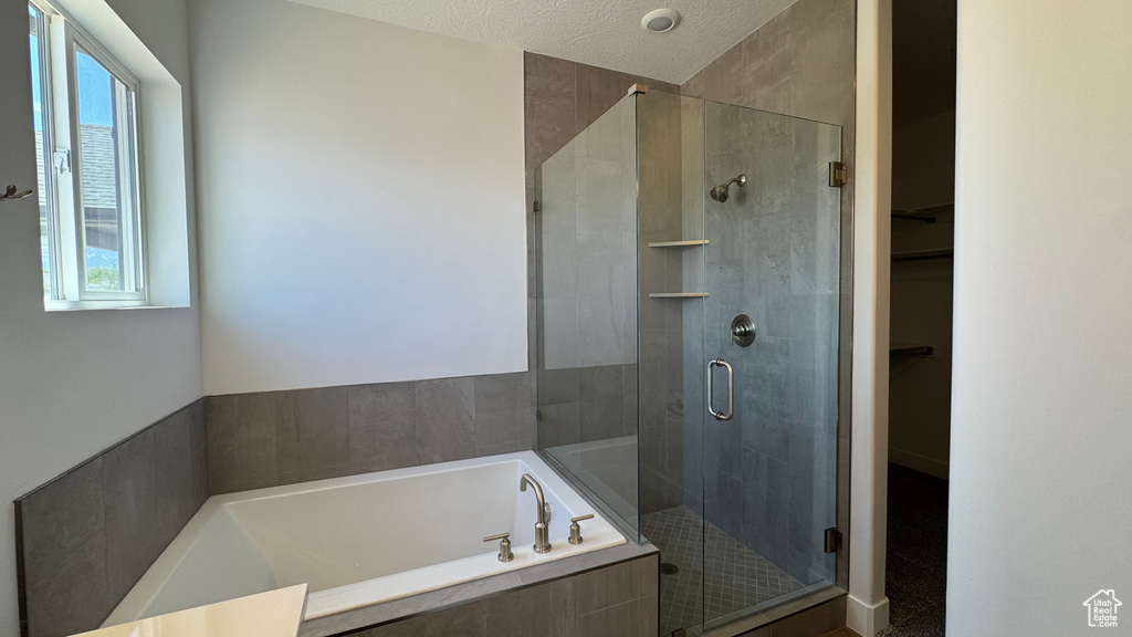 Full bath with plenty of natural light, a stall shower, a bath, and a walk in closet