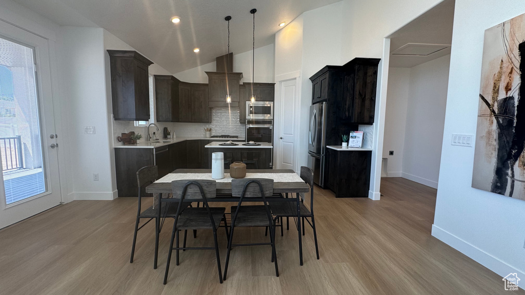 Kitchen featuring appliances with stainless steel finishes, baseboards, light wood-style floors, light countertops, and tasteful backsplash