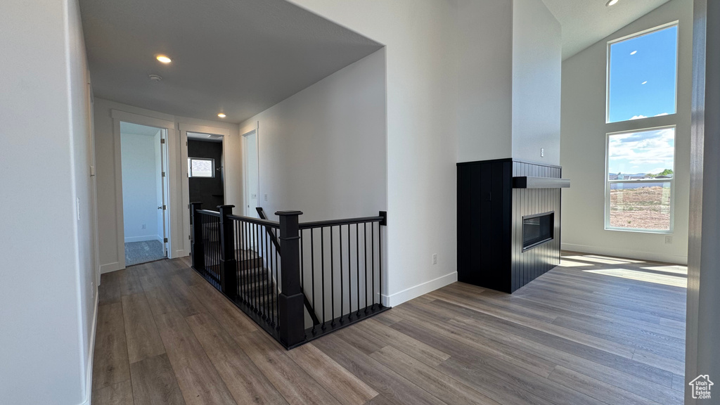 Corridor featuring wood finished floors, an upstairs landing, recessed lighting, baseboards, and a high ceiling