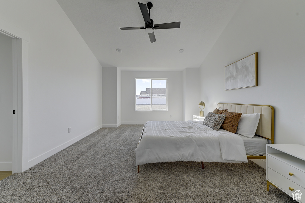 Carpeted bedroom featuring vaulted ceiling and ceiling fan