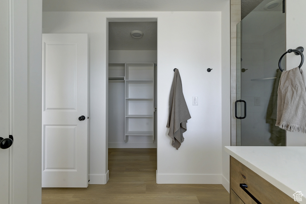 Bathroom with hardwood / wood-style floors, vanity, and a shower with door